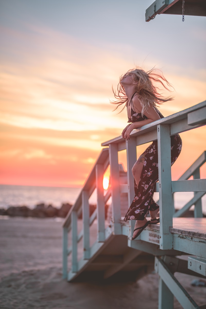 A little girl sitting on a railing at the beach